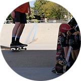 Skate teacher on board, group of children's legs wearing knee-pads in foreground